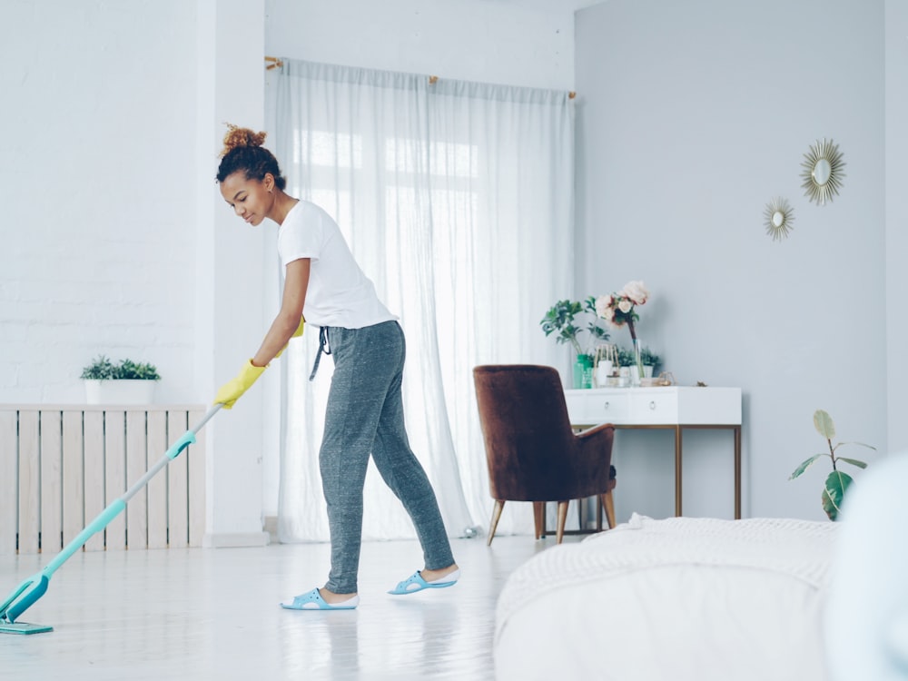 Cleaner mopping the floor of a bright, tidy bedroom